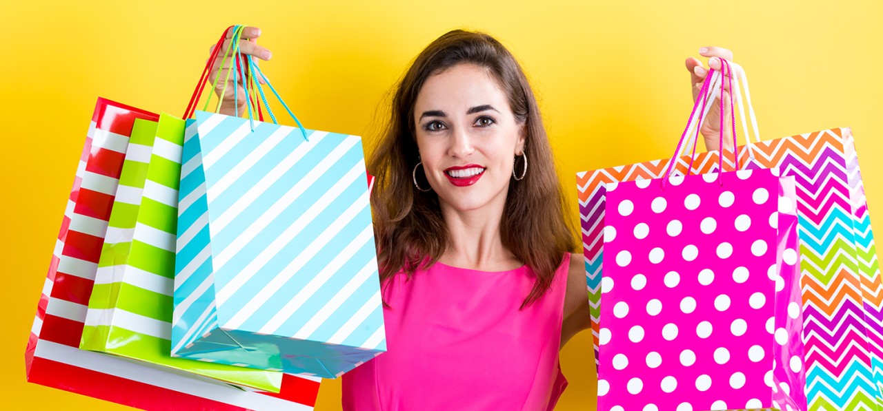 happy-young-woman-holding-many-shopping-bags-on-a-yellow-background-SBI-317641736