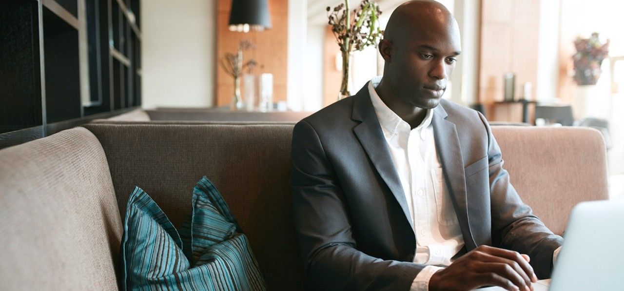 image-of-young-man-sitting-at-cafe-working-on-laptop-african-businessman-at-coffee-sho-SBI-301326743